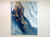 A video of an abstract art painting with blue and gold tones on a white wall