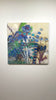A video of a blue and green abstracted encaustic painting hangs on a white wall.