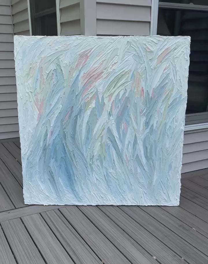 Video of an original Abstract painting with texture in blue, green, white, and pink leaning on a deck.