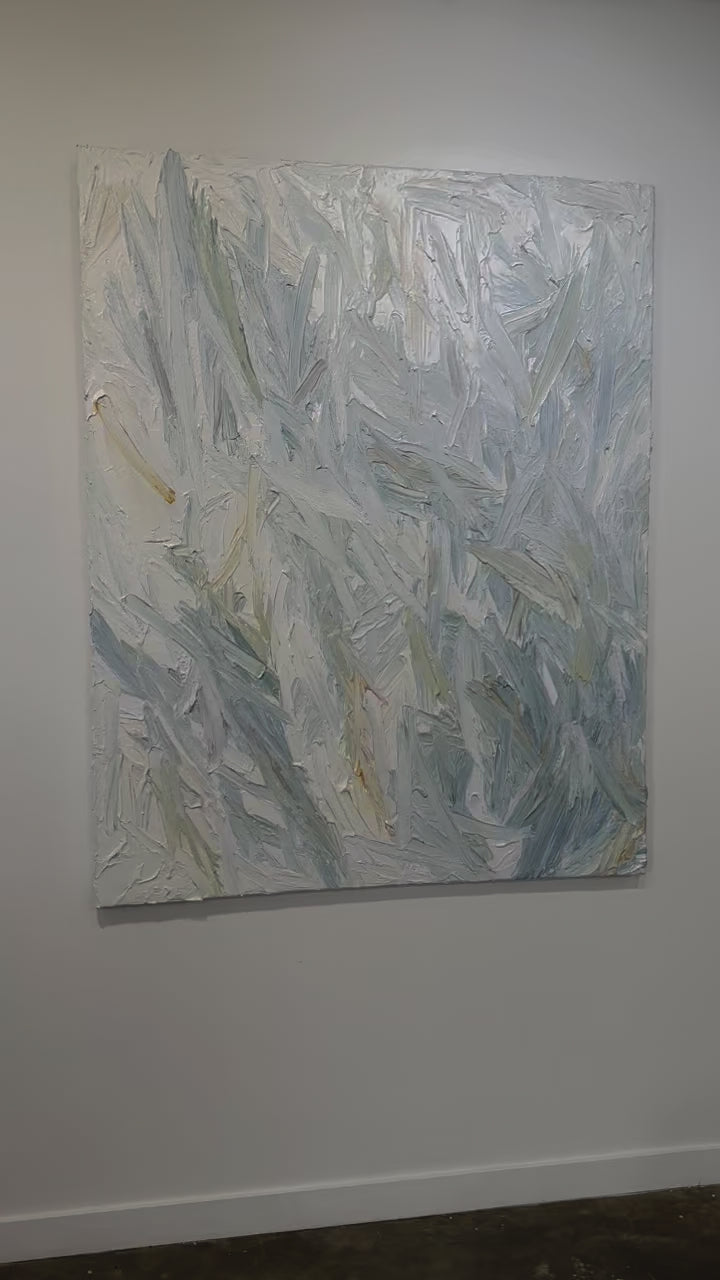 A video of an abstract painting with thickly textured blueish, orangish and greenish beige brushstrokes is hung on a gallery wall.