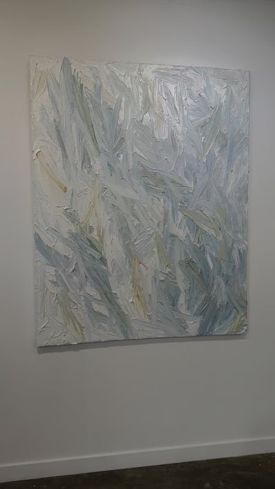 A video of an abstract painting with thickly textured blueish, orangish and greenish beige brushstrokes is hung on a gallery wall.