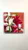 A video of a Floral artwork with red, white, and pink flowers on a textured red background hanging on a white wall.