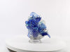 Video of glass sculpture of blue flowers in a clear vase on a white background.