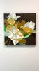 A video of a Floral painting with yellow, white, and green flowers on a dark background hanging on a white wall.
