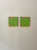 a video of two square abstract text based paintings with thick green paint and tangerine gestural lines, hanging on a white wall.
