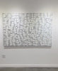 A vide of a white, grey, and silver abstract painting on the art galley wall.