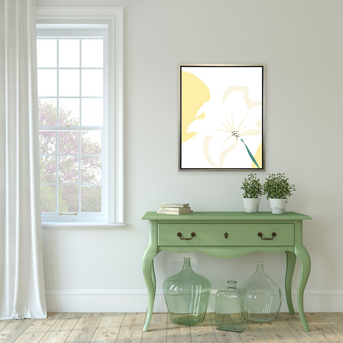 A light yellow abstract botanical art print framed in a white frame hangs on a wall next to a window and above a green console table with potted plants, books, and large green glass vases. 