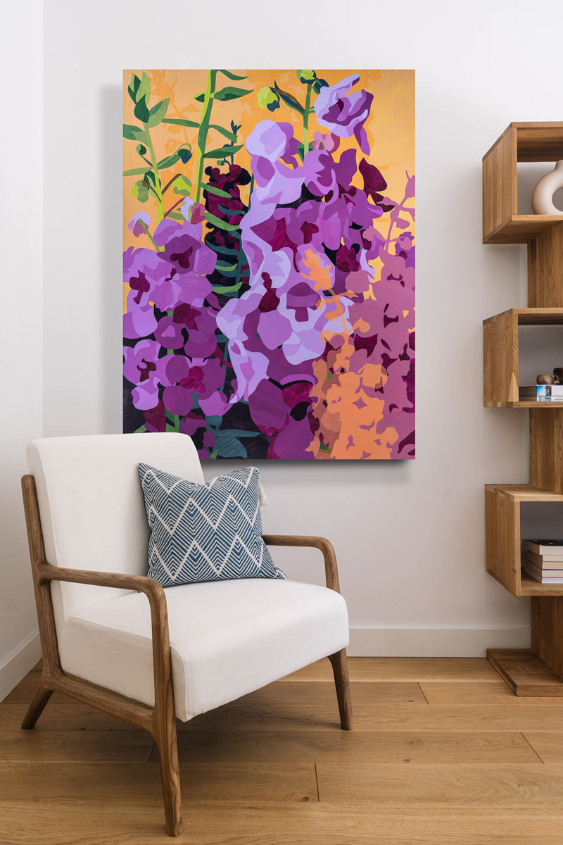 Colorful floral painting on a wall above a white armchair with a blue pillow.