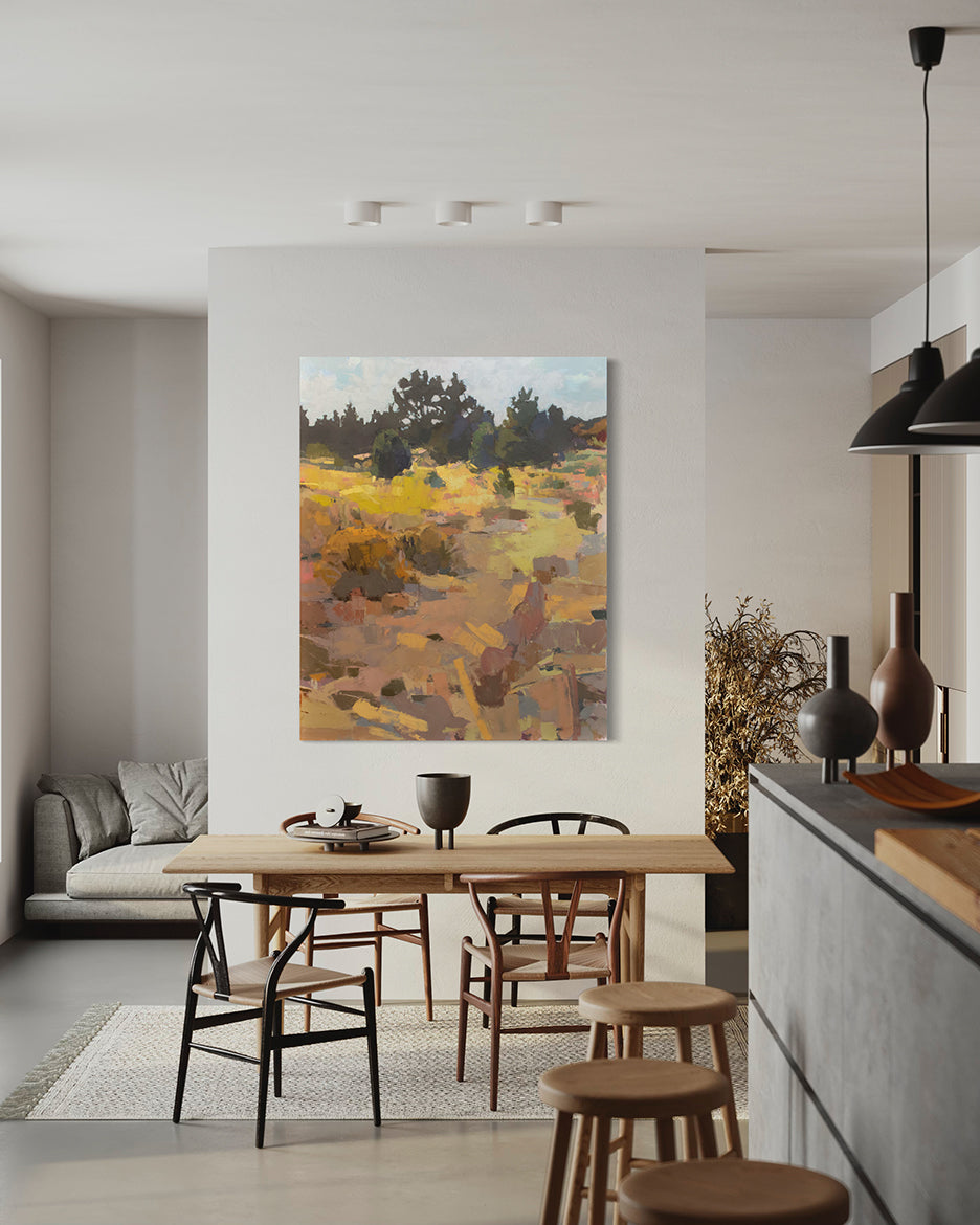 An abstracted landscape painting hangs on a white wall above a kitchen table.