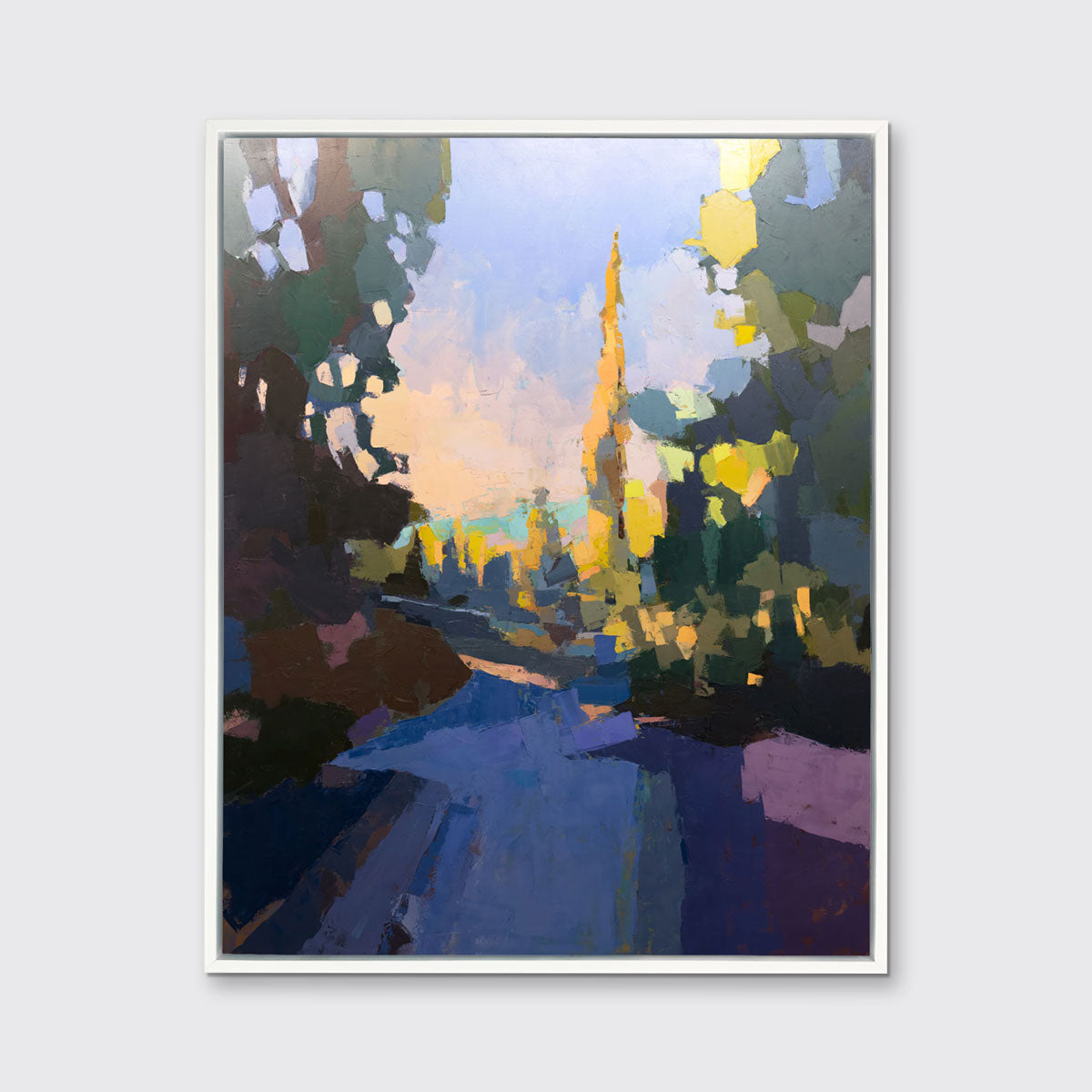 A blue abstract landscape art print framed in a white frame hangs on a white wall.