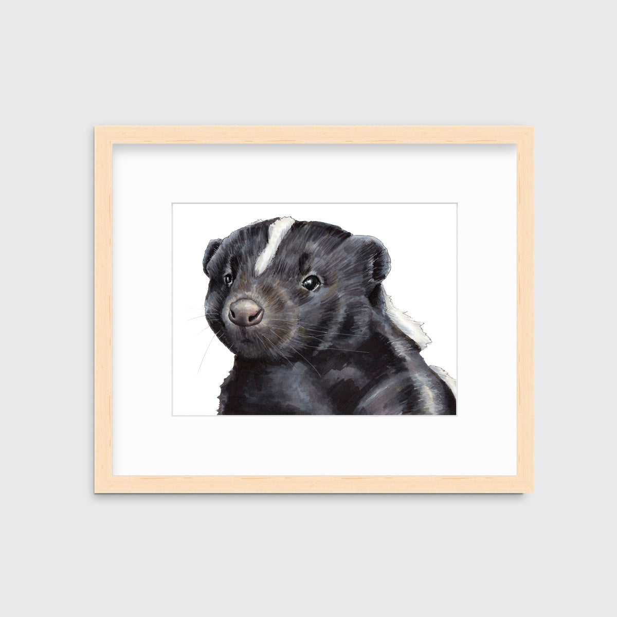An illustration of a skunk framed in a natural wood frame hangs on a white wall. 