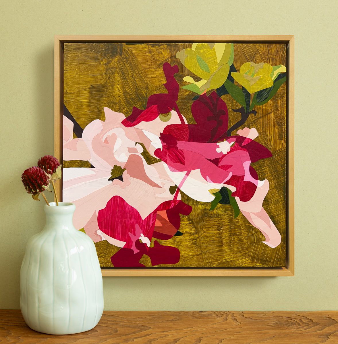 Framed abstract artwork with colorful flowers on a green wall.