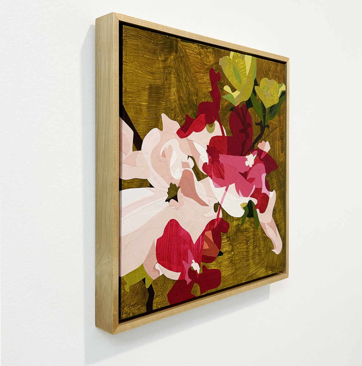 Framed abstract artwork with colorful flowers on a white wall, side view.