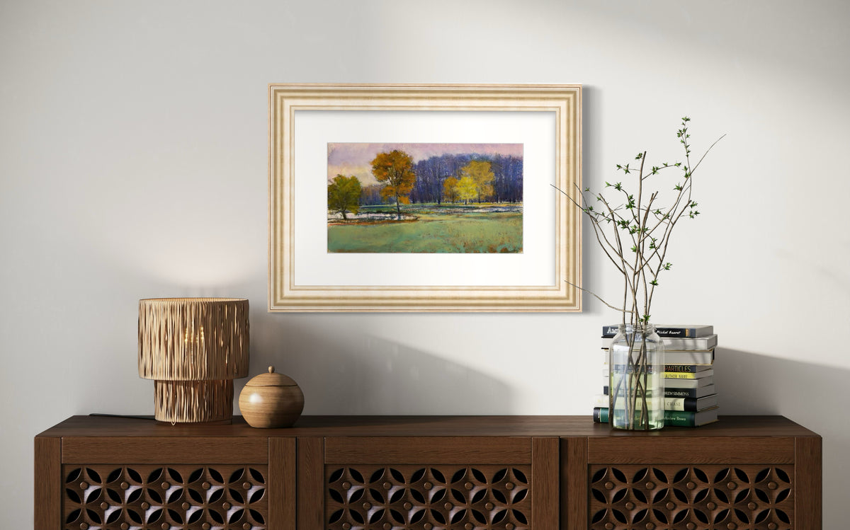 Framed landscape painting on a wall above a wooden console table with decorative items.
