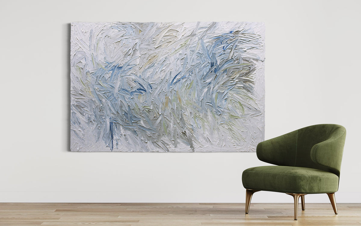 Abstract painting on a white wall with a green chair in front