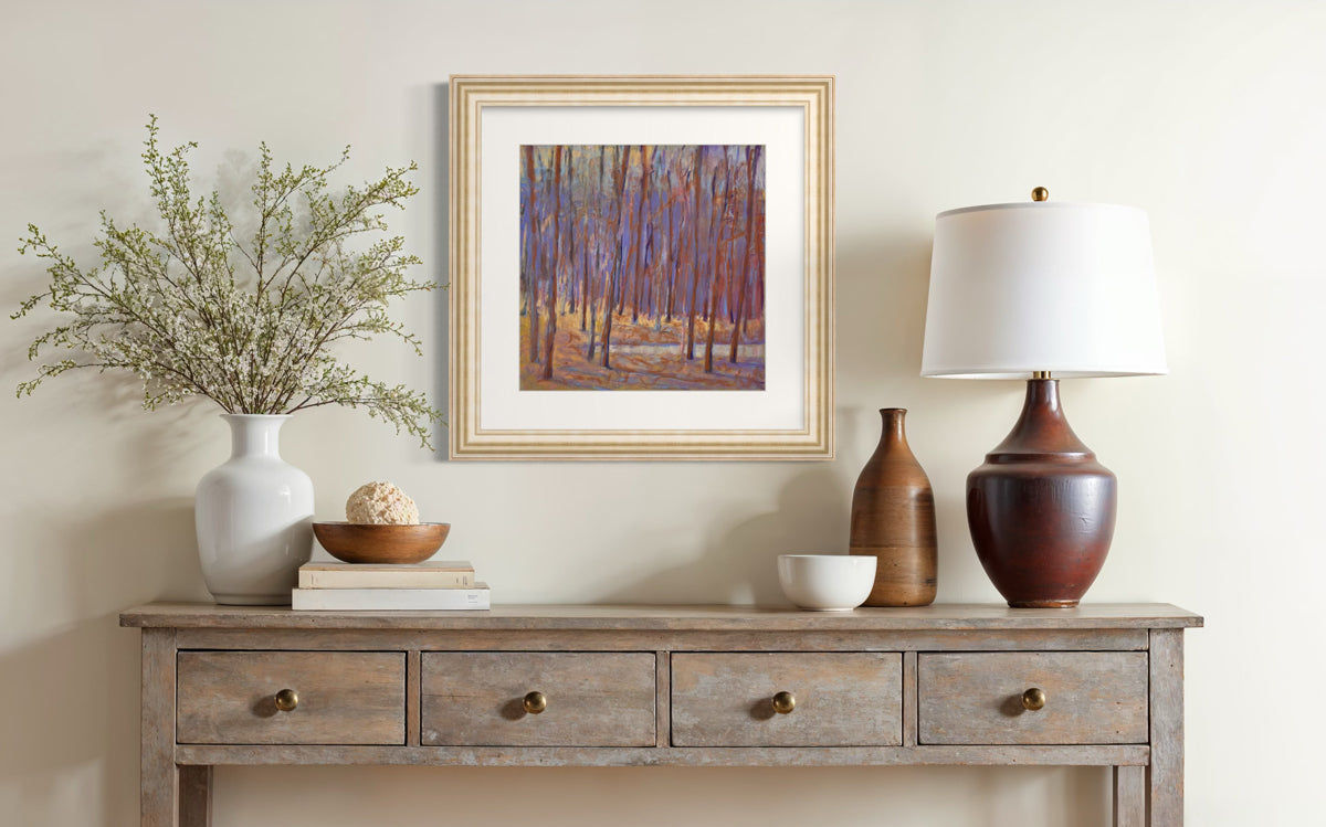 Decorative console table with a lamp, vase, and framed artwork against a beige wall.