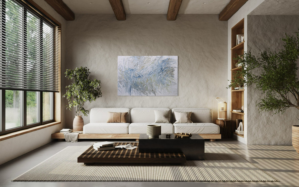 An abstract painting hangs over a sofa in a modern living room with a sofa, coffee table, and decorative elements.