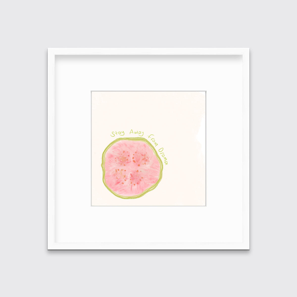 An abstract art print of a fruit with the words "stay away from drama" in a white frame with a mat hangs on a white wall.