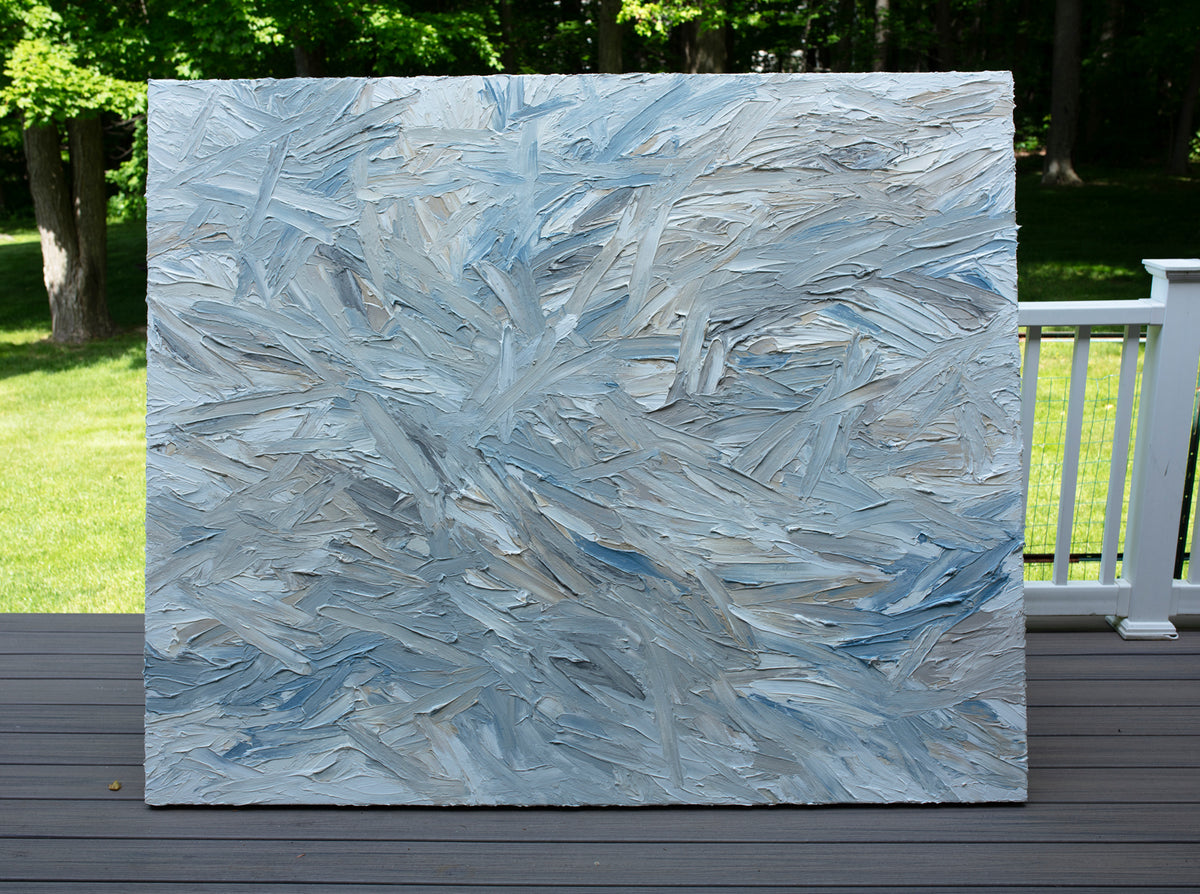 Original abstract painting by Teo Guererra with blue and gray tones on a wooden deck at her studio. 