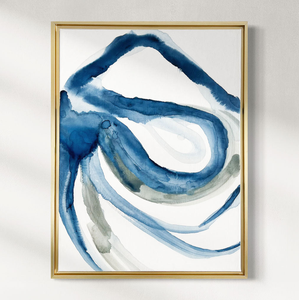 Abstract art print with blue and gray brush strokes in a gold frame on a white wall.
