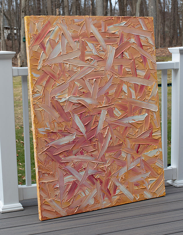 A orange, pink, coral and white textured abstract painting sits on the artists deck.
