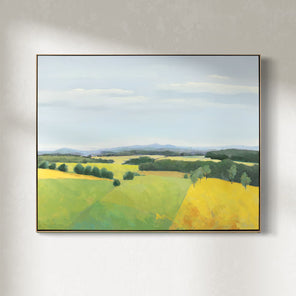 A framed blue and yellow landscape painting of a field hangs on a white wall.