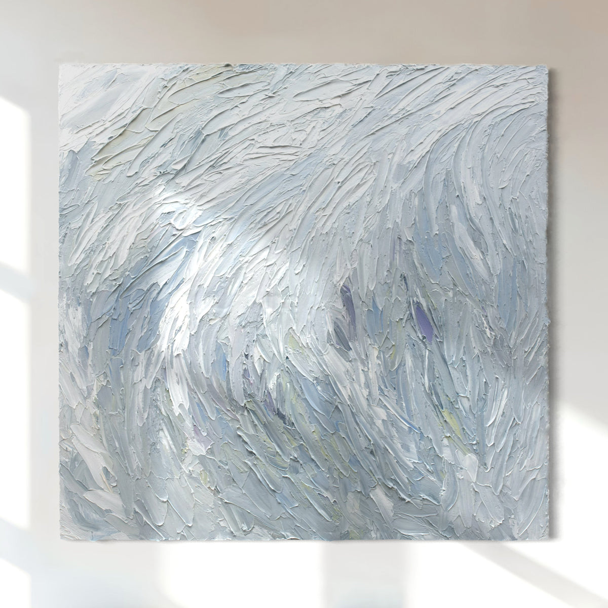 A Grey blue, light blue, lavender, celadon and white thickly textured abstract painting hanging on a white wall in natural light by Teodora Guererra.