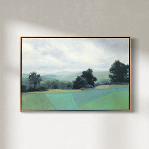 A green landscape painting framed in a light wood frame hangs on a white wall. 