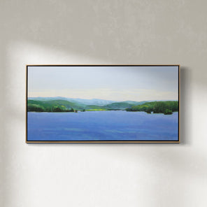 A blue and green landscape painting framed in a light wood frame hangs on a white wall. 