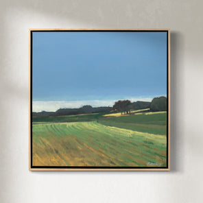 A green and blue abstracted landscape painting in a light wood frame hangs on a white wall. 