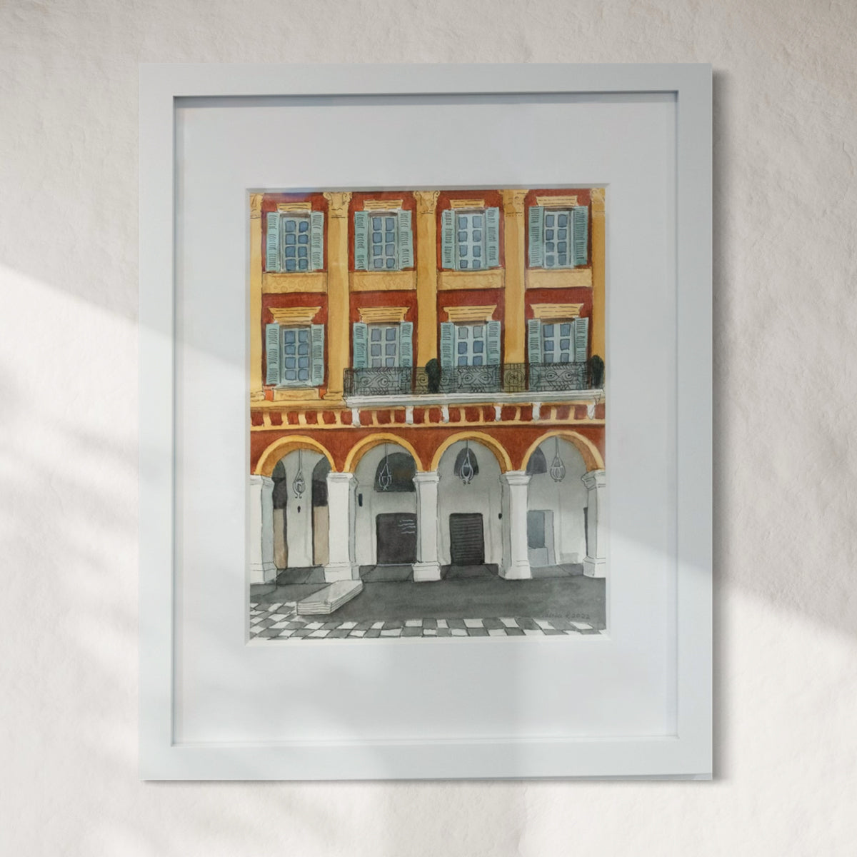 Framed artwork of a colorful building facade on a light gray background