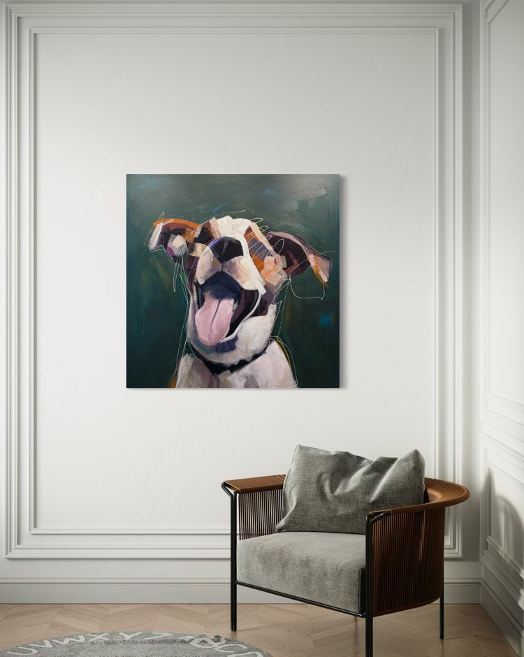 A square painting depicting a joyful dog with its mouth open, displayed on a white paneled wall above a modern armchair in a living room setting.