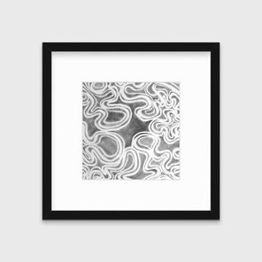 A grey and white abstract print in a black frame with a mat hangs on a white wall.