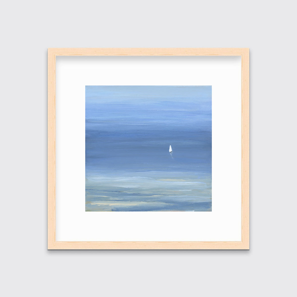 A blue, light green and white abstract seascape print with a small sailboat in a natural wood frame with a mat hangs on a white wall.