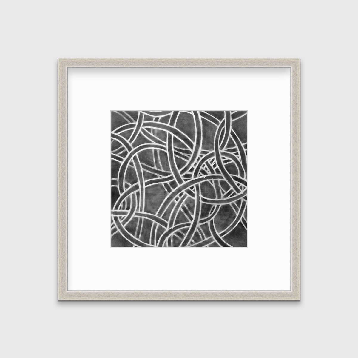 A dark grey and white abstract print in a silver frame with a mat hangs on a white wall.