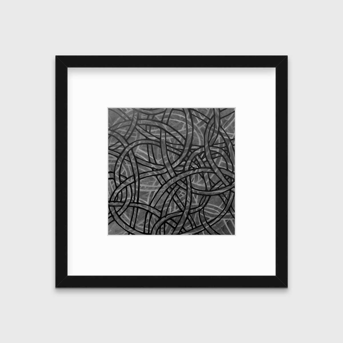 A grey, black and white abstract print in a black frame with a mat hangs on a white wall.