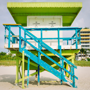 A front view photograph of a lime green, turquoise, and white lifeguard stand in Miami, Florida. 