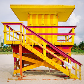 A front view photograph of a yellow, red, and orange lifeguard stand in Miami, Florida. 