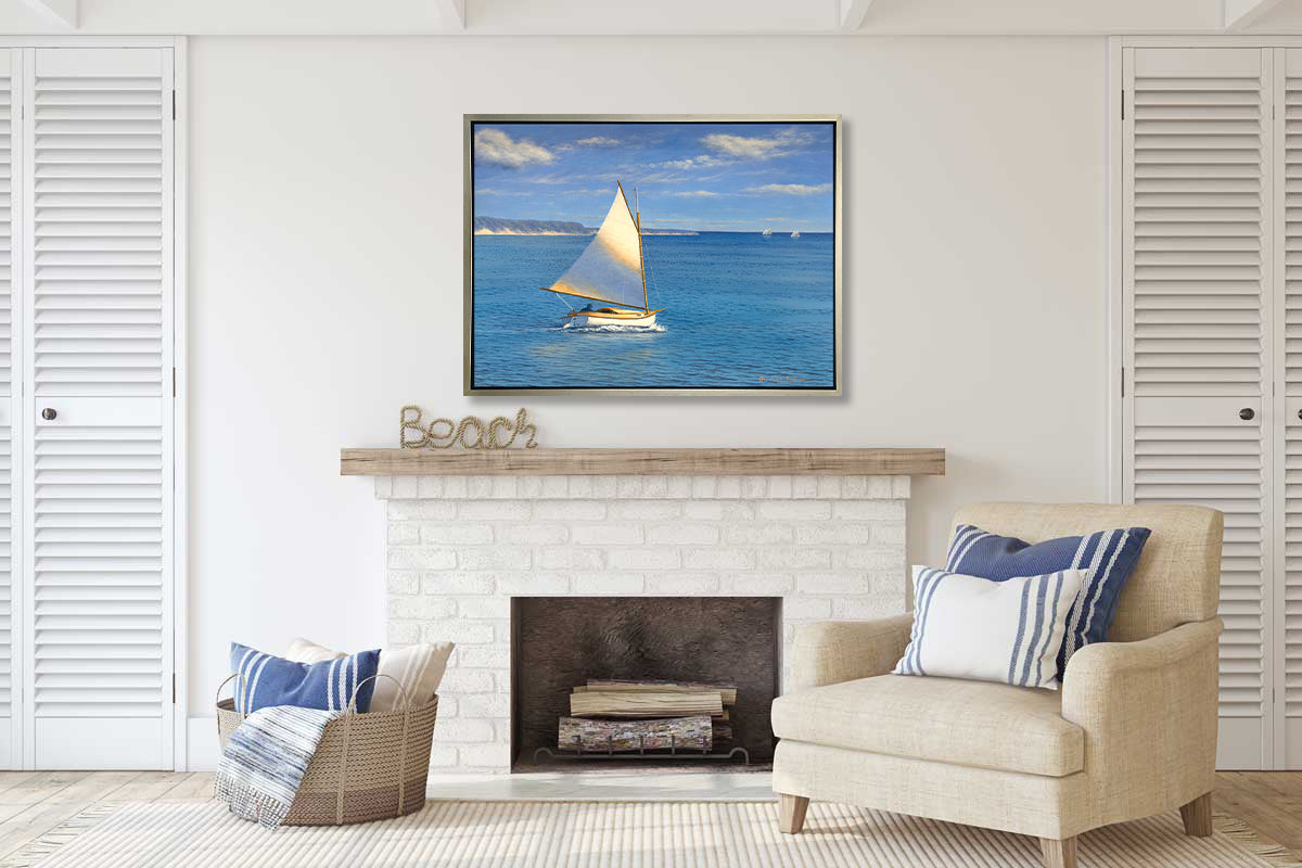 A blue, beige and white realist seascape print with a sailboat in a silver floater frame hangs on a white wall above a white brick fireplace, a white linen chair with pillows and a woven basket with pillows.