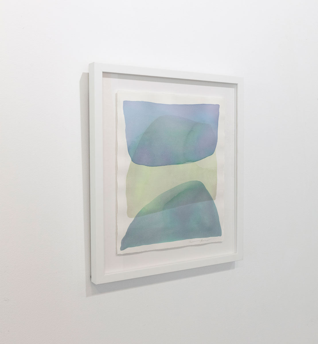 A watercolor of blue, green and dark turquoise forms overlapping is seen at an angle on a gallery wall. Wired and ready to hang.