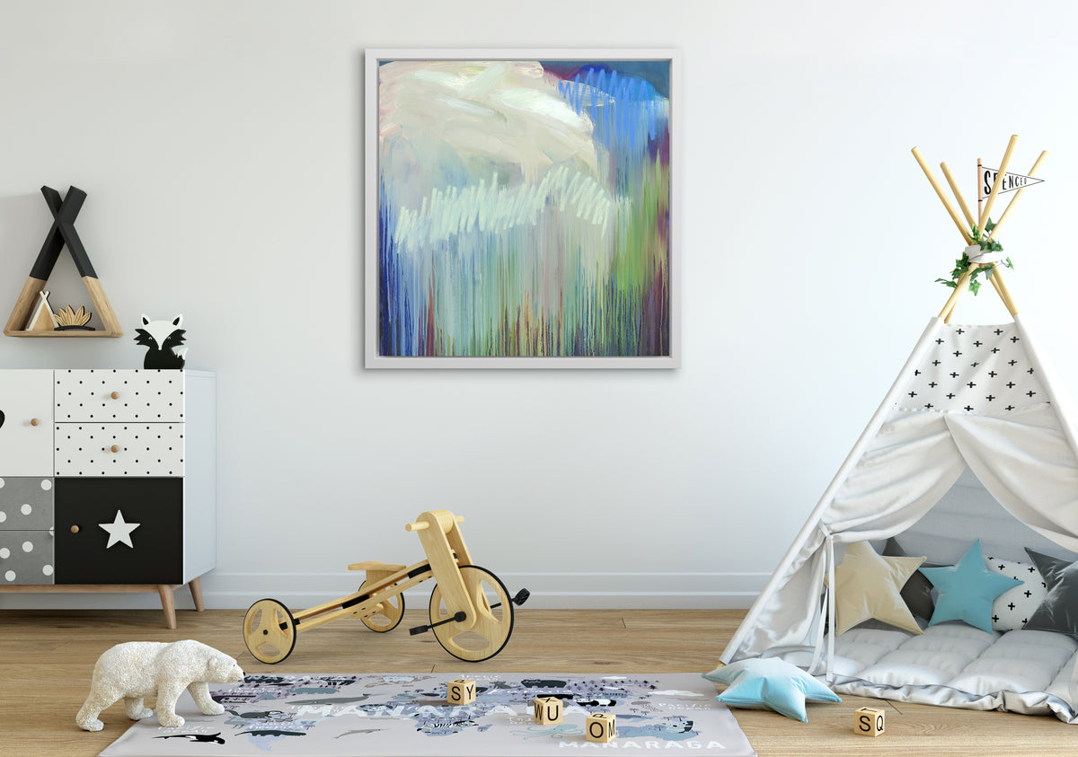A multicolored abstract print in a white floater frame hangs on a white wall above a white tepee tent, a wood tricycle and a black and white dresser with accessories.