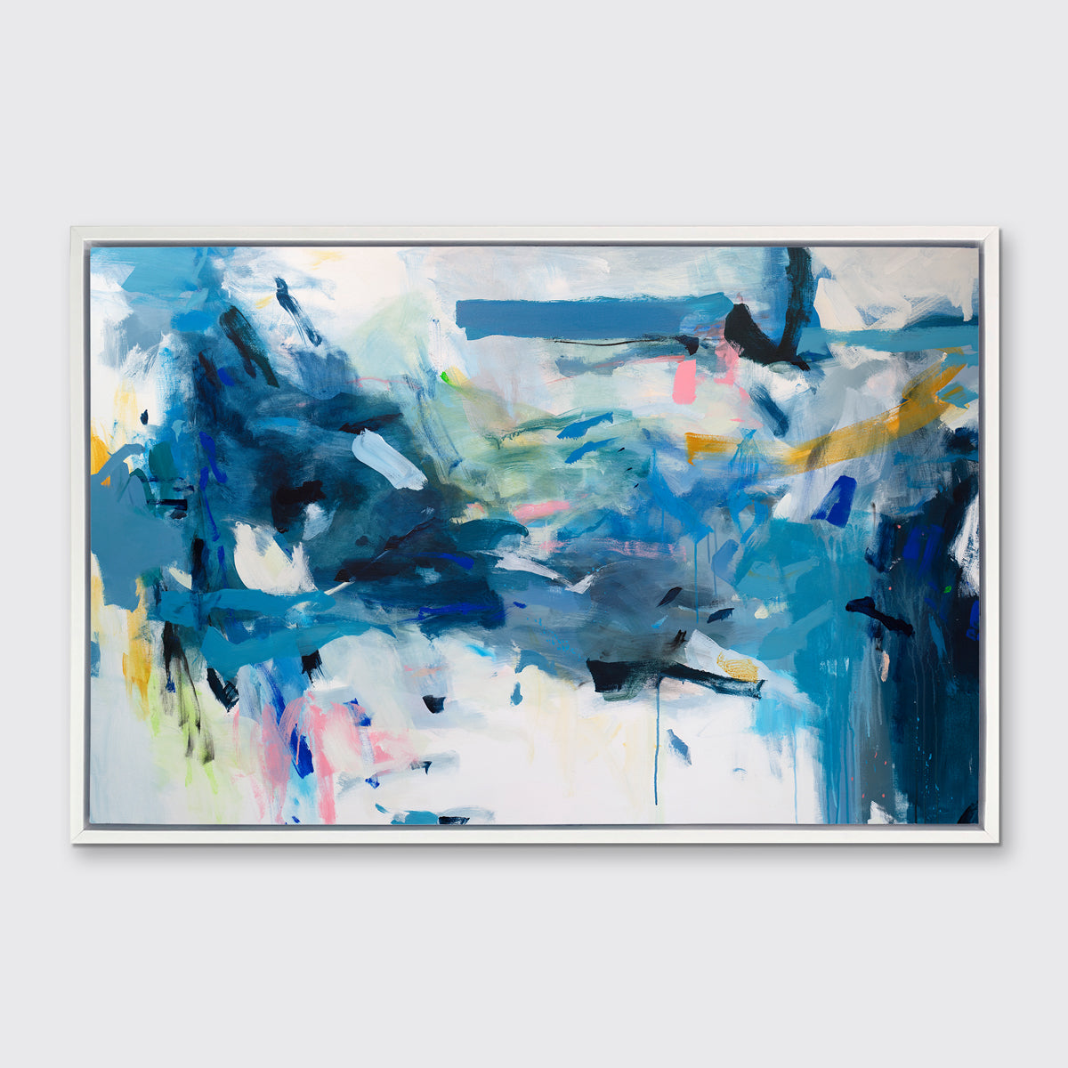 A blue, yellow and white abstract print in a white floater frame hangs on a white wall.