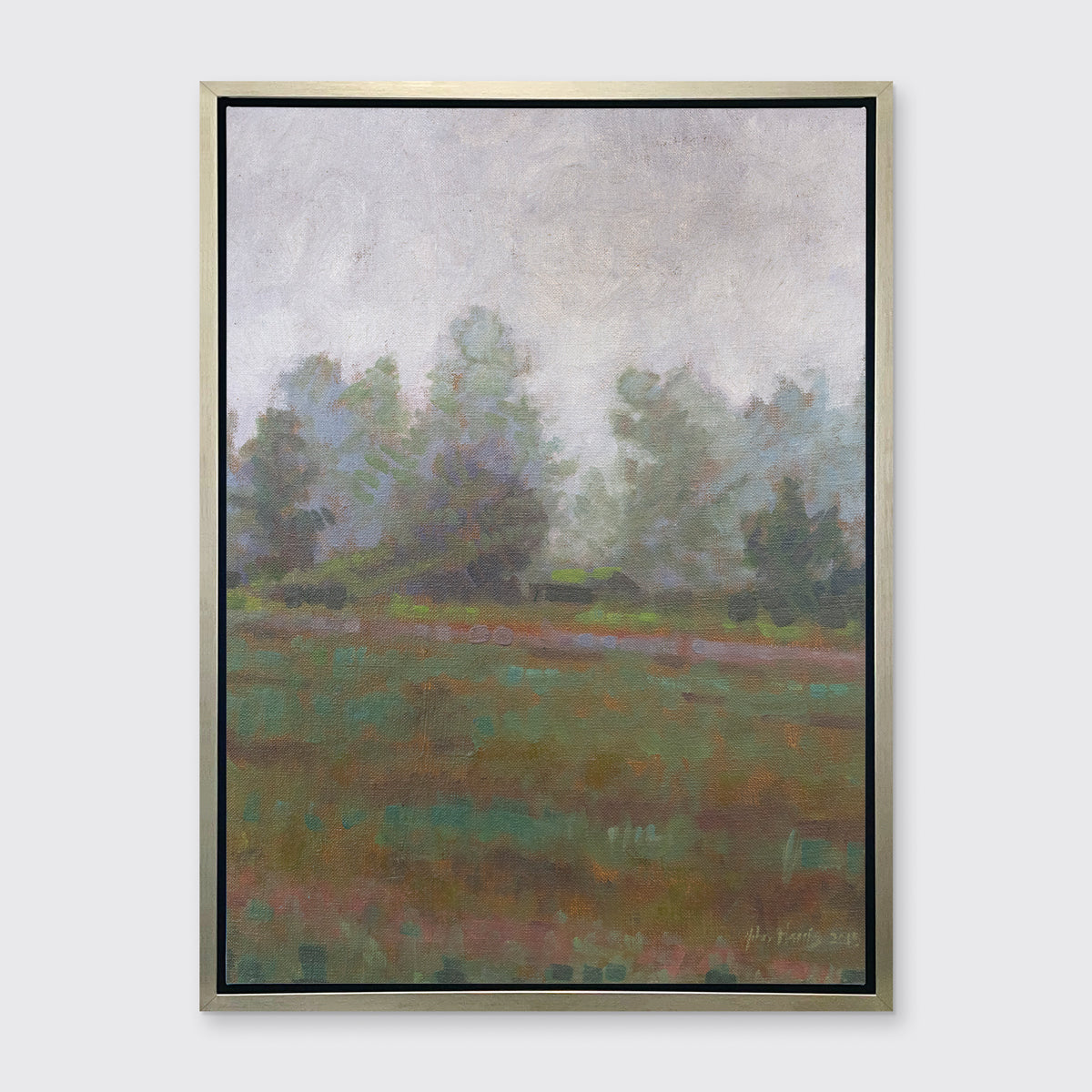 A grey and muted green abstract landscape print in a silver floater frame hangs on a white wall.