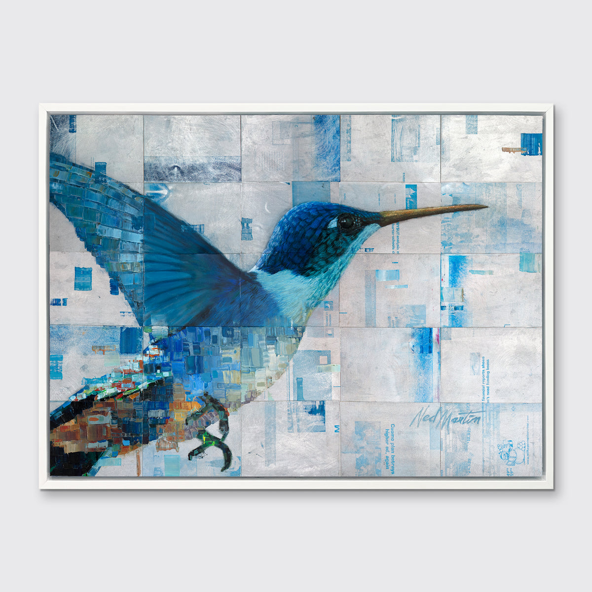 A blue and silver geometric abstract print of a hummingbird in a white floater frame hangs on a white wall.
