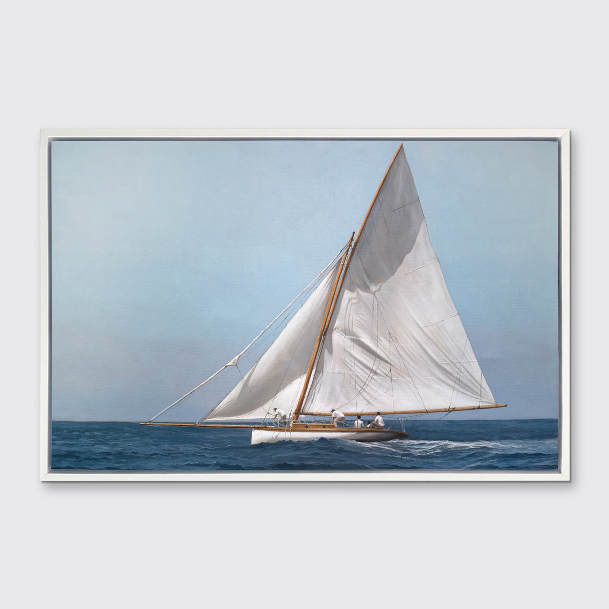 A blue, white and tan contemporary seascape print with a sailboat in a white floater frame hangs on a white wall.