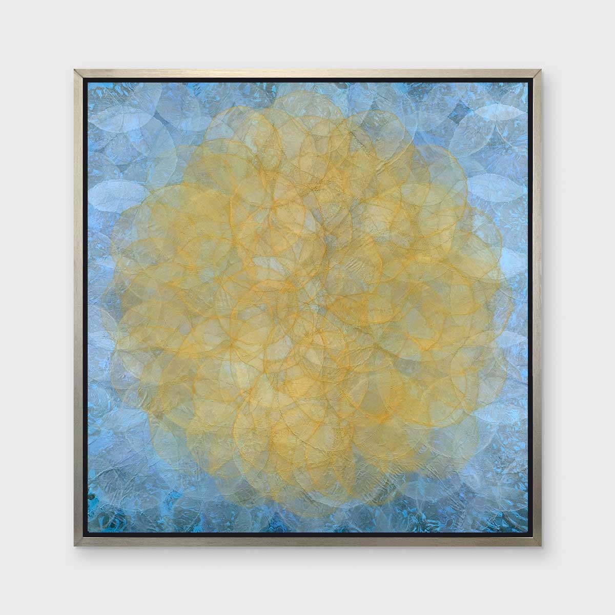 A blue, golden yellow and white abstract geometric print in a silver floater frame hangs on a white wall.