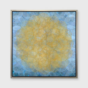 A blue, golden yellow and white abstract geometric print in a silver floater frame hangs on a white wall.