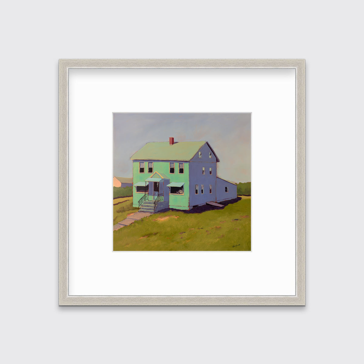 A seafoam green, blue and chartruse contemporary house print in a silver frame with a mat hangs on a white wall.