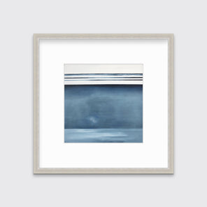 A blue and white abstract linear landscape print in a silver frame with a mat hangs on a white wall.