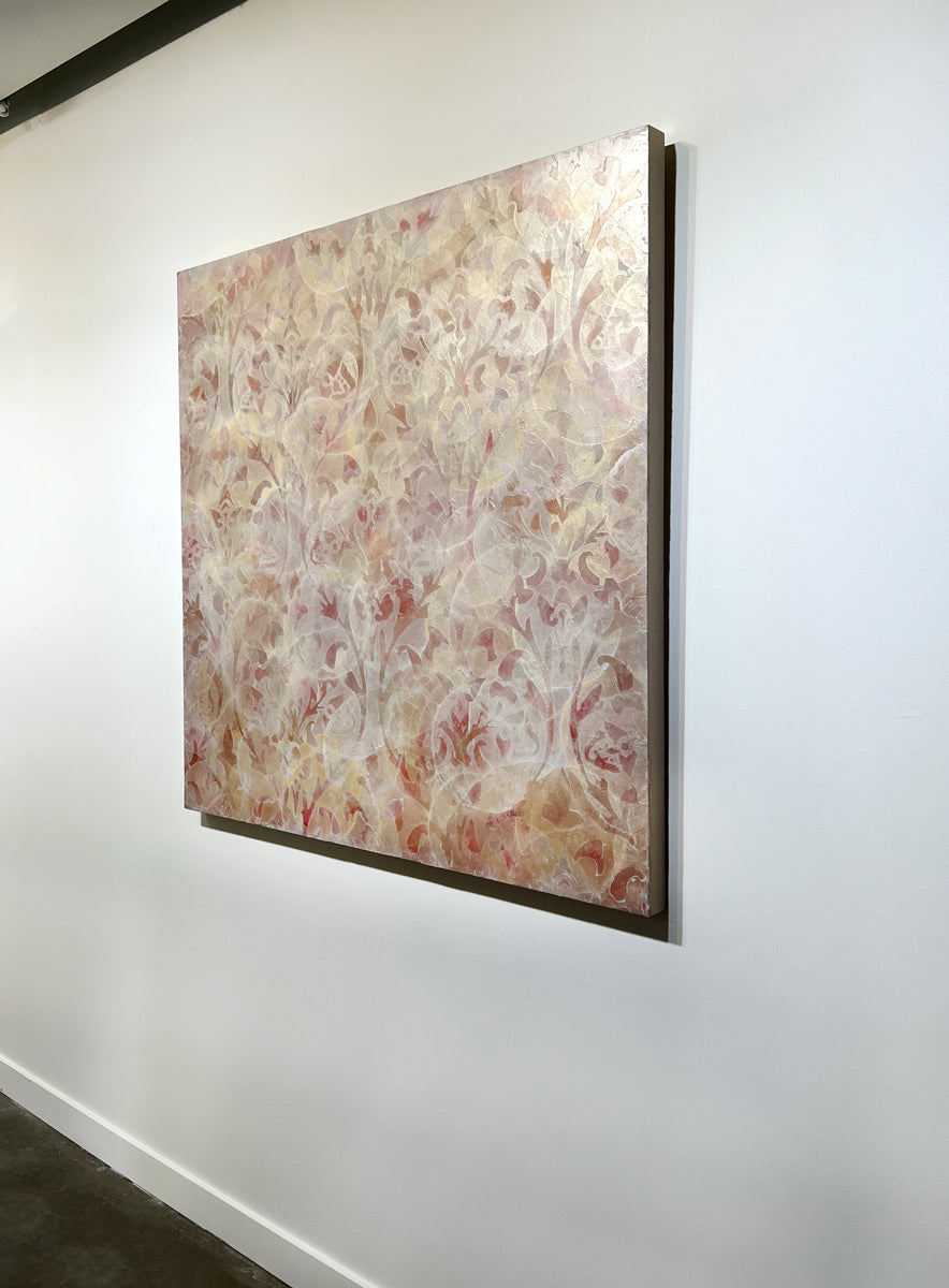 A right side-angle view of a coral, beige and gold-leaf abstract painting by Roger Mudre hangs on a white wall.